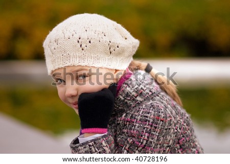 funny young blonde girl having nice time in park standing smiling with lifted hand in the park