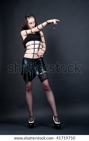 extravagant gothic emo girl pointing the way forward isolated on gray background