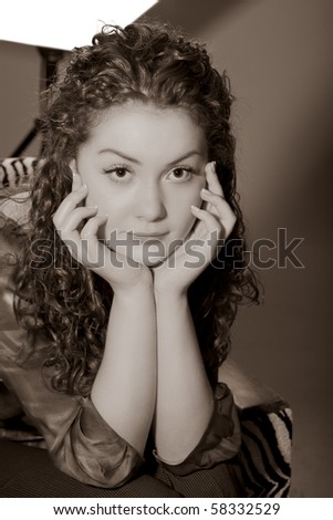 young and tired caucasian girl in studio sitting in chair with hands support and staring.picture made with color correction