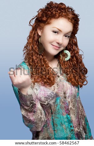 young nice caucasian red haired girl with pretty natural smile standing with lifted hand shaped and isolated over blue background