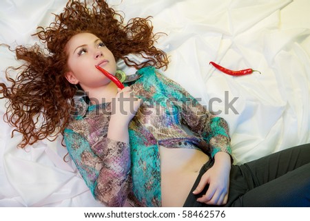 pensive young nice caucasian girl lying on white linen with two pepper pods and dreaming with sad look