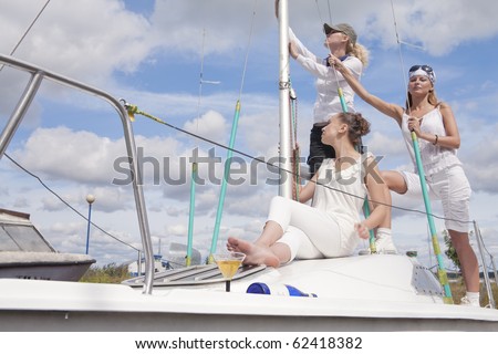 three young females with serious facial expressions standing on yacht board and expecting to set sail. shot made with studio strobe on location.