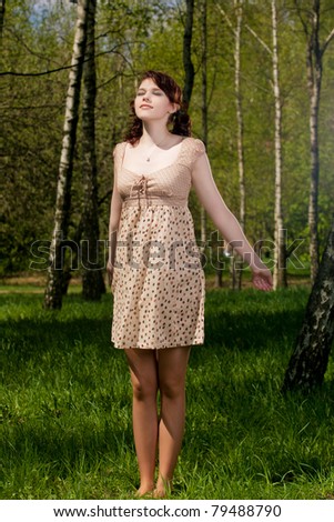 young and pretty caucasian brunette girl standing outside in green forest outside. shot made with strobes on location