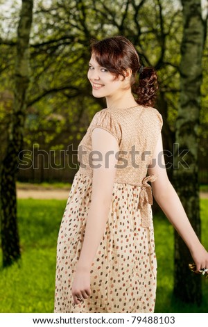 young and pretty caucasian brunette girl standing outside in green forest - outside. shot made with strobes on location
