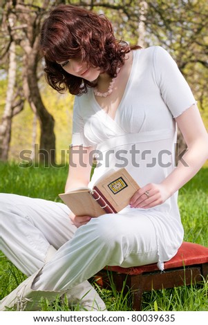 brunette caucasian girl in spring forest reading book-outside