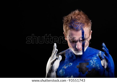 handsome caucasian man with body-art mozaic painting and face decoration standing against black background: part of body-art project