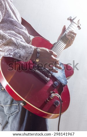 Male Guitar Player Performing with Electric Guitar Hands Closeup. Mixed Light Used. Vertical Image Orientation