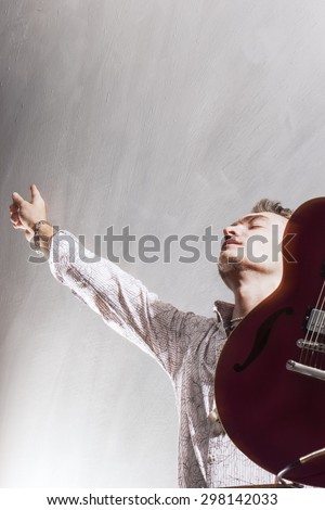 Praise and Worship Concepts. Young Caucasian Male Guitar Player Worshiping. Studio Shot. Against Gray. Vertical Image