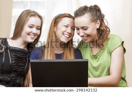 Friendship Concepts: Three Laughing Caucasian Girls Using Laptop and Having Good Time Together. Horizontal Image Composition