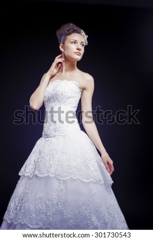 Wedding and Fashion Concept. Portrait of Young Caucasian Female Lady in Tailored Wedding Dress Made to Order Against Black. Vertical Image Composition