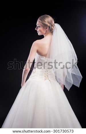Nice Portrait of Sensual Caucasian Female Bride in Beautiful Nicely Tailored Wedding Dress Posing Against Black. Vertical Image Orientation