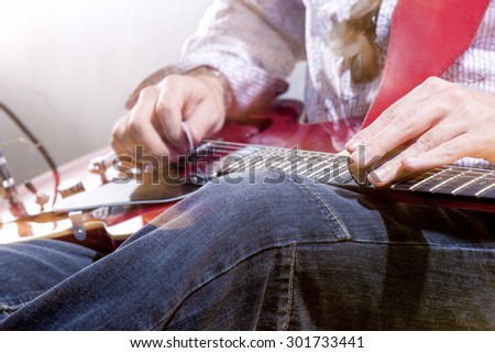 Professional Guitar Player with Electric Guitar Hands Closeup. Studio Environment. Horizontal Image Orientation