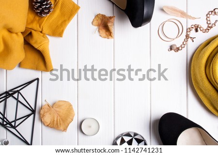 Autumn frame with female accessories. Shoes, yellow sweater and autumn leaves on a white wooden background top view