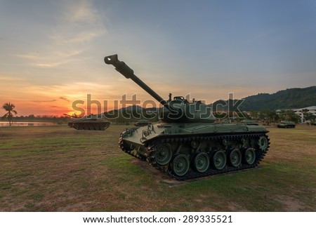 Military tank in the field during sunset.