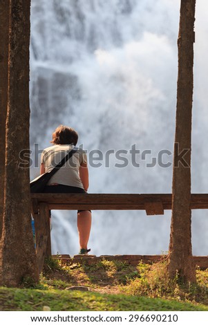 Lonely people sit on wooden seat bench at Water Fall.