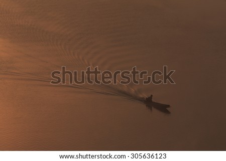 Silhouette Background of a boat is running through a river in the sunset time.