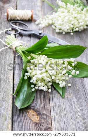 Bouquet of lilies of the valley on the table with a coil of rope and scissors on the background