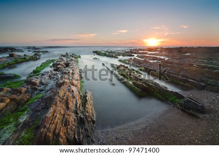 beautiful sunset on a rocky coastline with great detail on the first plane