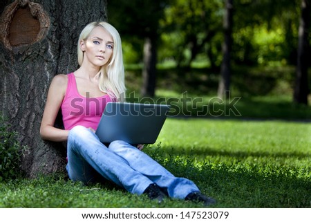 21 Mpx full-frame HD-capture.Portrait of a beautiful young blond woman sitting outdoor with laptop