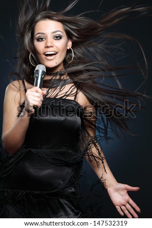 studio shot of a beautiful young singer on dark background