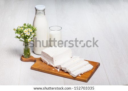 milk bottle and glass on wooden background, rural wildflowers bouquet, cottage cheese