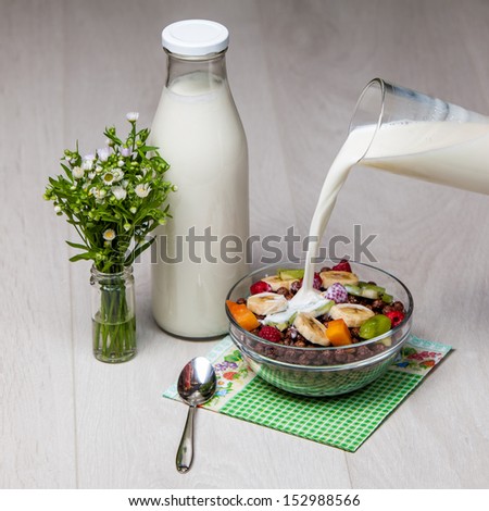 light breakfast - milk and chocolate corn flakes with berries and fruits on wooden background