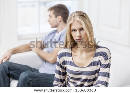 Upset young woman sitting with her husband in the background