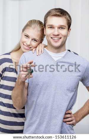 Young caucasian man holding keys and wife standing together - husband and wife
