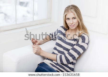 young beautiful blond woman laying on the couch with laptop