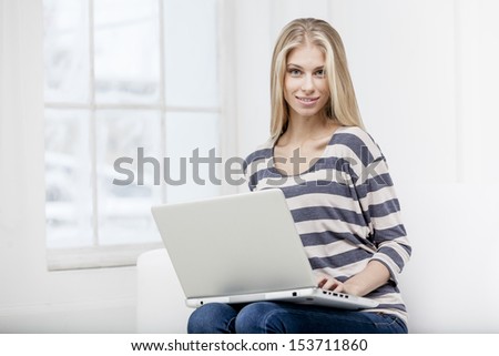 young beautiful blond woman sitting on the couch with laptop