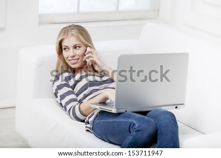 young beautiful blond woman laying on the couch with laptop
