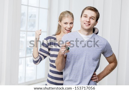 Young caucasian man holding keys and wife standing together - husband and wife