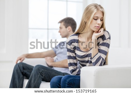 Upset young woman sitting with her husband in the background