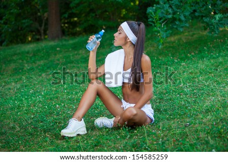 young beautiful brunette sportswoman resting outdoor holding bottle of drinking water