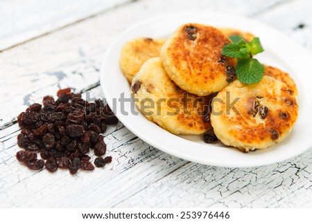 Delicious homemade cheese pancakes with raisins on rustic wooden table