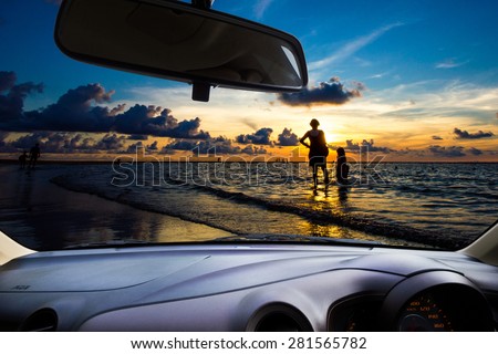 look out the car window to see the sunset on the beach for use as a background.