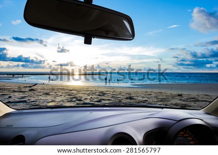look out the car window to see the sunset on the beach for use as a background.
