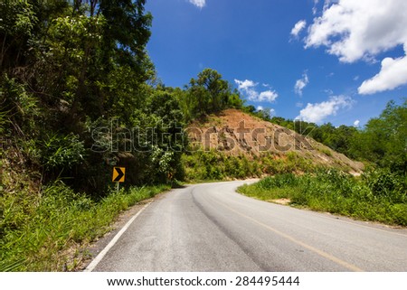 The forest road in Thailand,we can see forest,blue sky and mountain,use as a background.