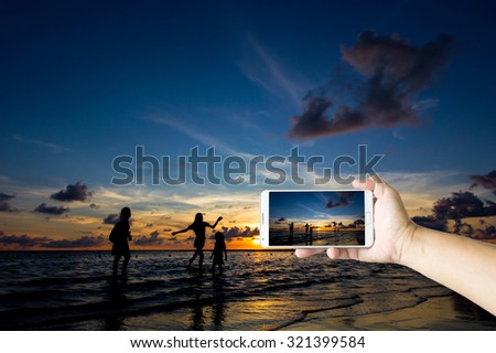 Man photographed sunset and his family on the beach with his Smart phone, Beautiful , sharp images and realistic , Phuket Thailand.