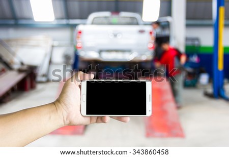 Girl use smart phone, blur image of shop and tire repair services as background.