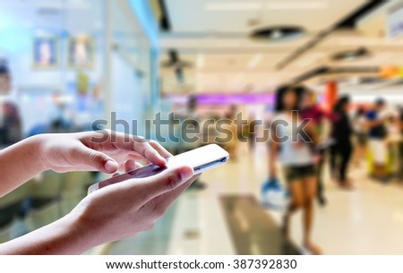 Girl use mobile phone, blur image of inside the mall as background.