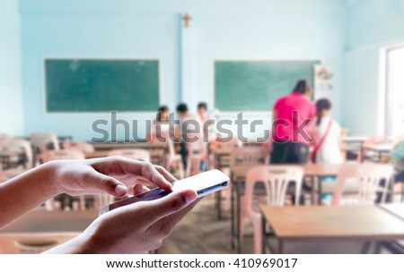 Girl use mobile phone, blur image parents of students and teachers are meeting as background.
