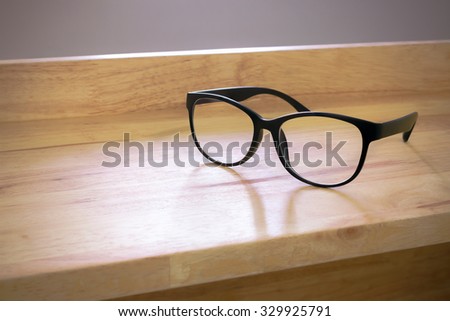 Vintage tone and black glasses. Hipster eyeglasses on table. Vintage tone. Black eyeglasses on wood background. Soft vintage tone and glasses. Hipster glasses. Relax time. Time to rest. Chill time.