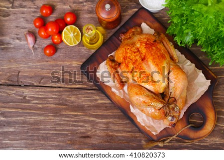 baked chicken with a golden crust with vegetables on a wooden background
