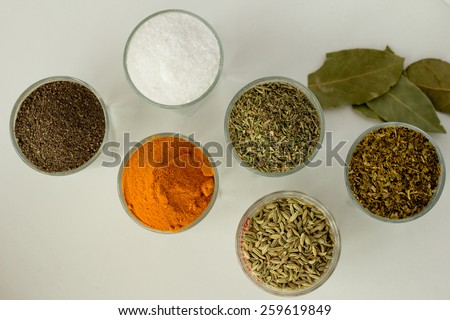 Spices and herbs in six small glasses