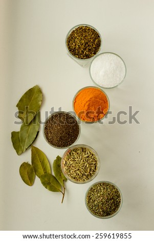 Spices and herbs in six small glasses top view