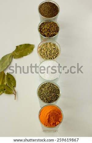 Spices and herbs in six small glasses top view