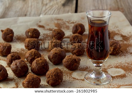 Shot of small glass of cognac and homemade candies wooden table