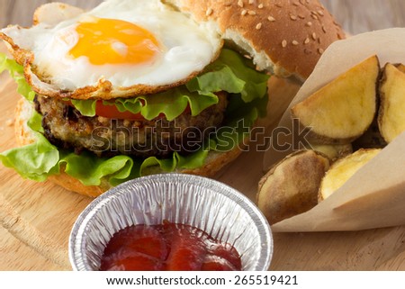 Shot of burger with fried egg and roasted potato wedges