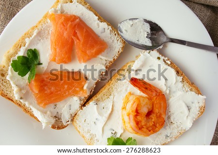 Wheat bread toasts with cream cheese, smoked salmon and shrimp selective focus top view